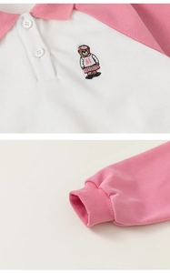 Detailed close-up of pink and white polo shirt featuring cute bear embroidery and ribbed cuffs