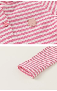 Dettaglio della trama in maglia a coste a righe rosa e toppa con orsetto sulla maglietta