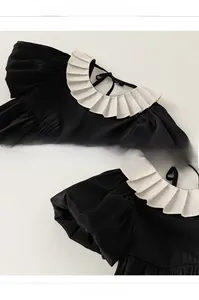 Detail view of the vintage black toddler dress with white ruffled collar and puff sleeves