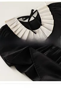 Detail of Peter Pan collar with bow and fine stitching on a girl's black dress