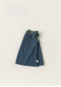 Detailed close-up of girls' dark wash denim pinafore dress with brown buttons and neat seams