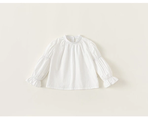 Detail of white cotton girls long sleeve shirt with ruffled collar and elastic cuffs