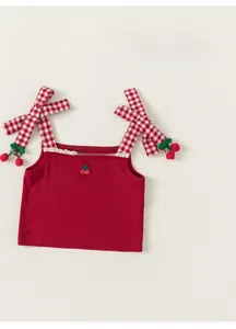 Close-up of red knit camisole with checkered bow straps and cherry hanging details