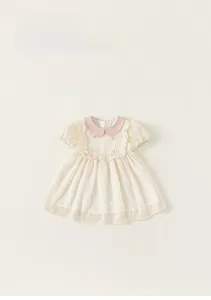 Detailed close-up of pink Peter Pan collar and bow knots on striped baby dress