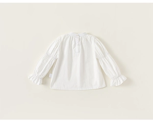 Detail of white cotton girls blouse with ruffled sleeve cuffs and elegant mock neck
