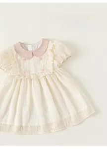 Detail view of girls off-white cotton dress with pink Peter Pan collar and bow accents