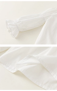Detail of ruffled elastic cuffs and smooth hem on a white cotton girl's dress