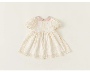 Detail of baby girl dress showing cream fabric with 3D dots and pink Peter Pan collar