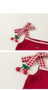 Detail of red ribbed cotton kids tank top featuring gingham bow straps and crochet cherries