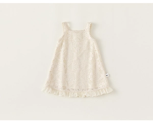 Close-up of cream crochet girl's dress showing hollow diamond patterns and ruffled edges