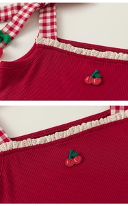 Detail of red ribbed girls top with lace trim, cherry embroidery and checkered straps