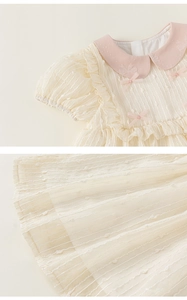 Detail of baby girl princess dress featuring 3D jacquard fabric and pink bows