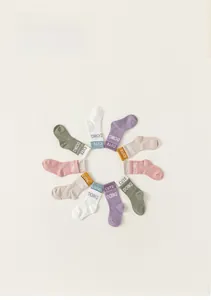 Dettaglio di calzini colorati in cotone per bambini con scritta bianca Cute Doing