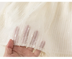 Close-up of off-white mesh fabric with vertical wavy texture and delicate 3D embroidery dots