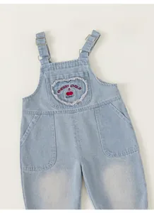 Detail of girls denim dungarees with heart embroidery and cherry pattern design