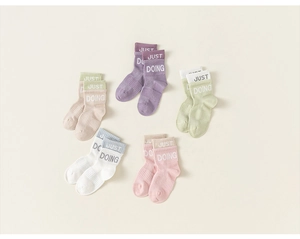 Dettaglio ravvicinato di calze di cotone per bambini con ricamo del testo Just Doing