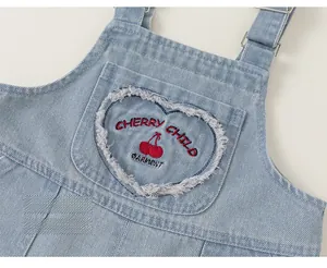 Detail of denim overalls with heart-shaped pocket and red cherry embroidery design