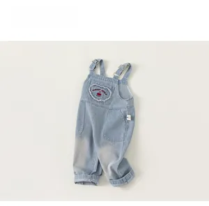 Detail of light blue denim overalls featuring heart embroidery and cherry design