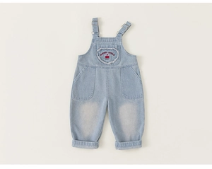 Detail of light blue denim overalls with heart-shaped cherry embroidery and adjustable buckles