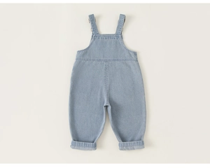 Macro detail of light blue wash denim overalls with metal buckles and neat stitching