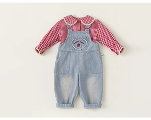 Close-up of girls' red gingham shirt with lace trim and denim heart overalls