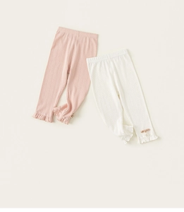 Detail of baby leggings with ribbed texture, ruffled cuffs and bow pearl accents