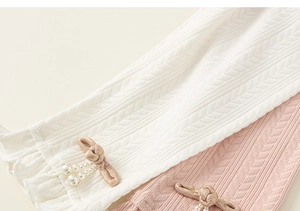 Detail of knit leggings showing ruffled cuffs and champagne bow with pearl accent