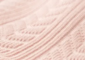 Detail showing soft pink knitted texture with wavy vertical patterns on girls leggings