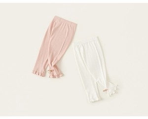 Detail of knitted girls' leggings with vertical hollow patterns and bow ribbon cuffs