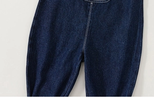 Detailed close-up of dark blue denim trousers featuring premium white double stitching