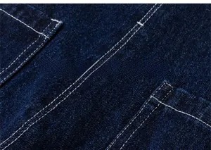 Macro detail of dark blue denim fabric with white contrast double stitching