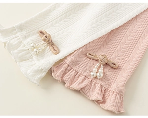 Close-up of knit leggings with herringbone texture, ruffles, and pearl button details