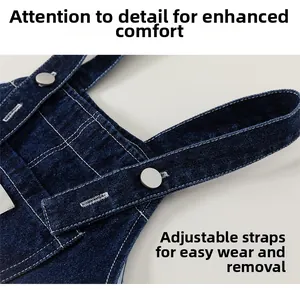 Detail view of dark blue denim overalls with adjustable straps and silver metal buckles