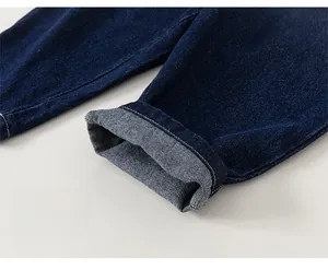 Detailed close-up of dark blue denim trousers featuring elastic cuffs and folded leg hem