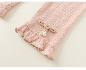 Close-up of pink knit leggings featuring a delicate bow and pearl bead decorations