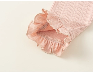 Close-up of pink knit trousers featuring chevron texture and delicate ruffled edge