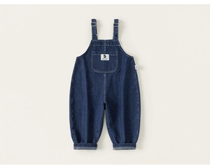Detailed macro view of dark blue denim overalls with adjustable straps and front pocket
