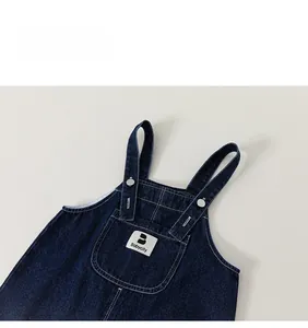 Detailed close-up of dark blue denim overalls with front pocket and Babycity label