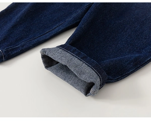 Detail showing the inner lining and neat stitching of rolled-up dark blue denim jeans cuffs