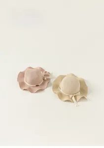 Dettaglio di cappelli di paglia per bambina con tesa ondulata e fiocco decorativo elegante