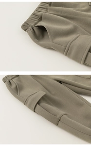 Detail view of olive green cargo pants showing elastic waistband and side pocket texture