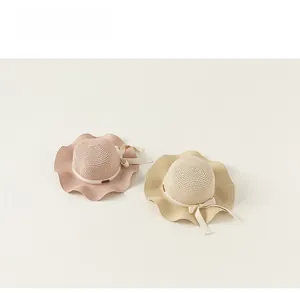 Dettaglio di cappelli di paglia estivi per bambine con tesa a onde e nastri a fiocco