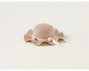Dettaglio del cappello di paglia per bambina con tesa ondulata e fiocco decorativo