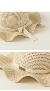 Dettaglio del cappello di paglia per bambini con fiocco in nastro e etichetta in pelle