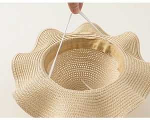 Dettaglio del cappello di paglia con tesa a onde e cinturino sottogola elastico