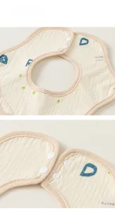 Détail du bavoir en coton pour bébé avec boutons-pression et texture de tissu doux