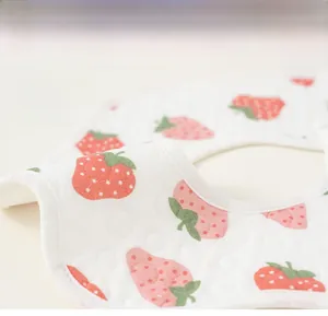 Détail du bavoir en coton matelassé pour bébé avec motifs fraises et coutures