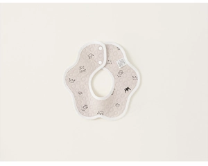 Détail d'un bavoir fleuri en coton pour bébé avec imprimé couronne et boutons pression