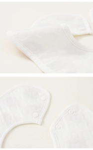 Détail du bavoir bébé blanc imperméable avec boutons-pression et texture de tissu fine