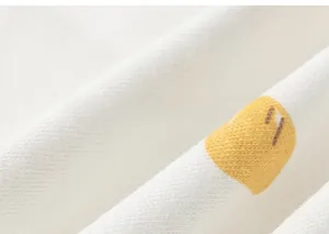 Gros plan sur un tissu en coton blanc doux avec motif animal jaune et texture fine